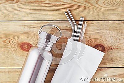 Aluminum bottle and metal tubes in cotton bag on a wooden background. Reusable eco friendly items. Zero waste eco friendly concept Stock Photo