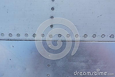 Aluminum surface of the aircraft fuselage. Smooth rows of rivets, there are scratches, dirt Stock Photo