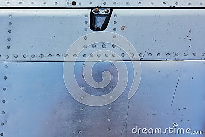 Aluminum surface of the aircraft fuselage. Smooth rows of rivets, there are scratches, dirt Stock Photo