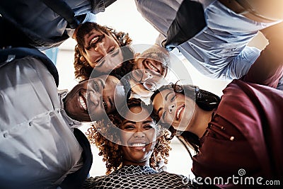 We alway put our heads together. Low angle portrait of a team of happy businesspeople putting their heads together in a Stock Photo