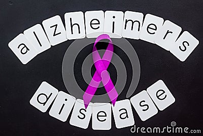 Alzheimers disease text near violet ribbon on black background top view Stock Photo