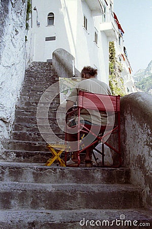 AMALFI, ITALIA, 1992 - A painter, quietly sitting down a steep staircase, chooses calmly the colors to paint on his canvas the Editorial Stock Photo