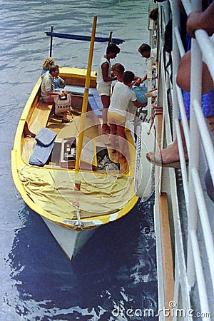 AMALFI, ITALY, 1974 - A young sailor helps tourists in the traditional landing in Amalfi. Editorial Stock Photo