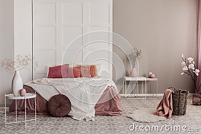Amaranth pillow and dirty orange bedding on king size bed in fashionable bedroom interior Stock Photo