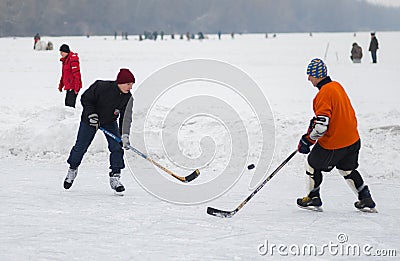 Amateur pair young and mature men playing hockey on a frozen river Dnepr in Ukraine Editorial Stock Photo