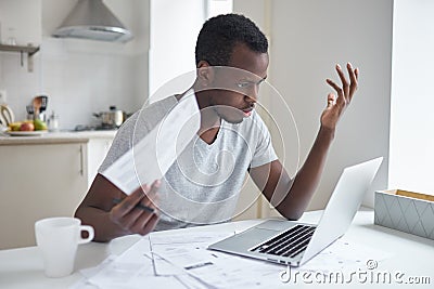 Amazed african american man stressed over bills is in complete shock unable to pay bills Stock Photo
