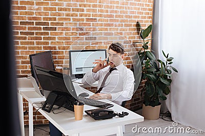 young businessman sitting near computers, smartphone Stock Photo