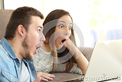 Amazed couple on line with a laptop Stock Photo
