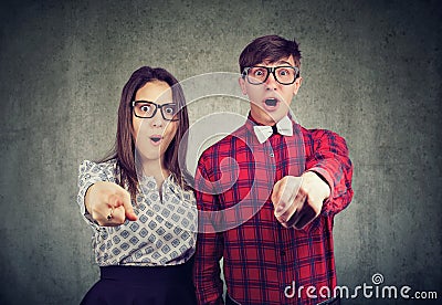 Amazed couple looking surprised at camera pointing fingers at you Stock Photo