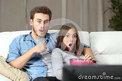 Amazed couple watching tv at home Stock Photo