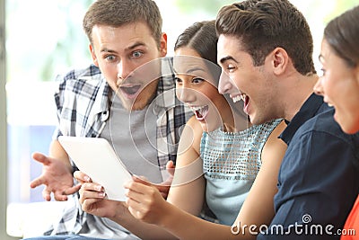 Amazed friends watching media in a tablet Stock Photo