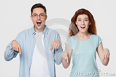 Amazed happy couple pointing fingers below indicating unbelievable sale offer Stock Photo