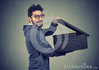 Amazed happy hipster man in hoodie and glasses opening a box with secret Stock Photo