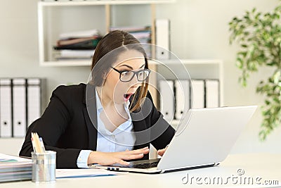 Amazed office worker reading good news in a computer Stock Photo