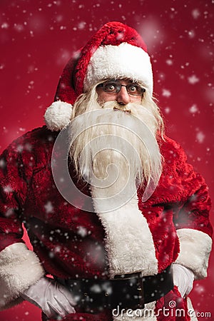 Amazed santa claus standing with hands on waist while snowing Stock Photo