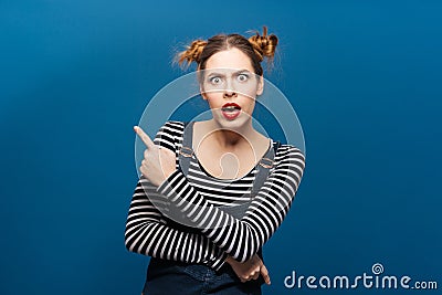Amazed shocked young woman with mouth opened pointing away Stock Photo