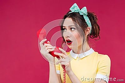 Amazed shocked young woman talking on telephone with red receive Stock Photo