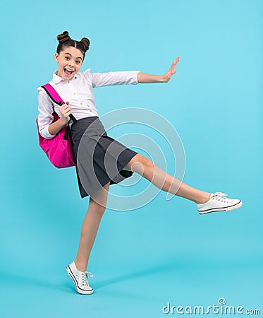Amazed teenager. Schoolgirl in school uniform with school bag. Teenage girl student on blue background. Jump Stock Photo