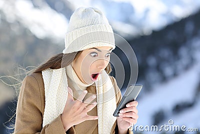 Amazed woman reading on line news in winter Stock Photo