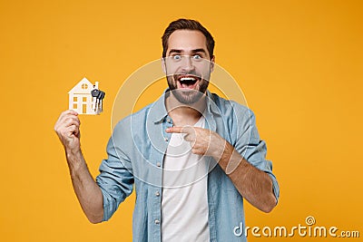 Amazed young man in casual blue shirt posing isolated on yellow orange wall background, studio portrait. People Stock Photo