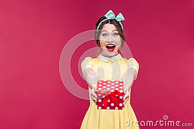 Amazed young woman holding and giving present box to you Stock Photo