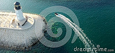 Amazing aerial drone view of lighthouse, dam and motor boat on Lustica bay near Tivat, Montenegro on sunny day. Picturesque view Stock Photo