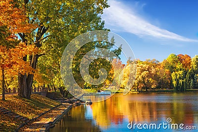 Amazing autumn landscape on clear sunny day. Colorful trees reflected in water surface of lake in park. Beautiful autumnal park Stock Photo