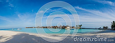 Amazing beautiful tropical beach panorama of water bungalos near the ocean with palm trees under the blue sky at Maldives Stock Photo