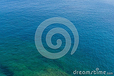 Amazing blue sea with sparkling highlights and green algae off the coast. Background of sea water Stock Photo