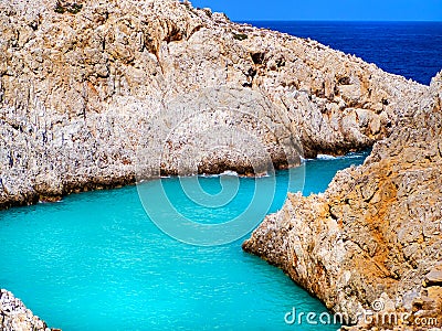 Amazing bright blue water in a secluded cove with orange cliffs surrounding it - Crete, Greece Stock Photo