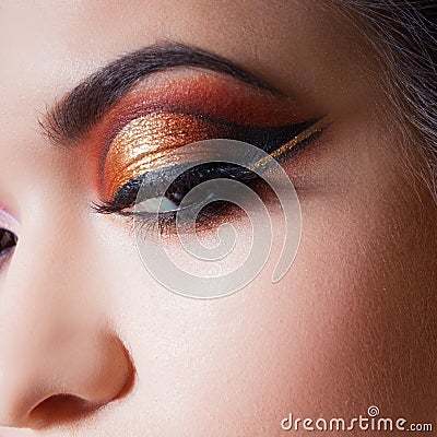 Amazing Bright eye makeup with a spectacular arrow. Brown and gold tones, colored eyeshadow Stock Photo