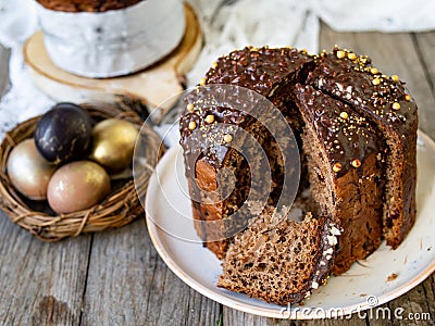 Amazing Chocolate Easter Cake with chocolate drops and dry cherries on an old wooden background with black and golden eggs. Slice Stock Photo