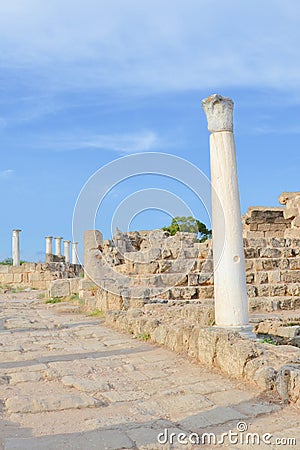 Amazing Corinthian columns captured on a vertical picture with antique ruins in the background and blue sky above Stock Photo