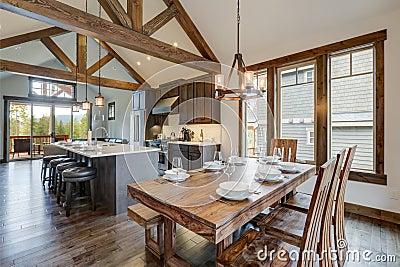 Amazing dining room near modern and rustic luxury kitchen with vaulted ceiling and wooden beams, long island with white quarts Stock Photo