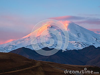 Amazing fiery dawn on a snowy mountain. Sunlight in the mountains. Big glacier on top in pink light. Scenic mountain landscape Stock Photo