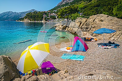 Amazing gravelly beach with colorful parasols and towels Stock Photo