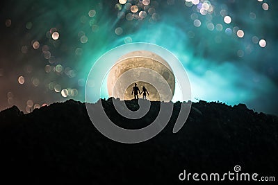 Amazing love scene. Silhouettes of young romantic couple standing under the moon light Stock Photo