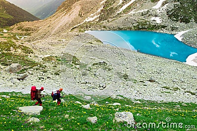 Amazing mountain sunny landscape with blue lake and two tourists Editorial Stock Photo