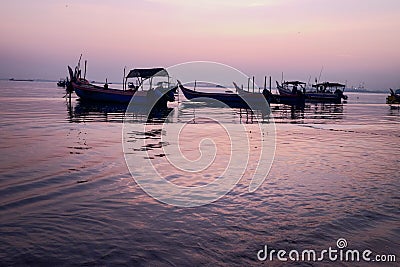 Fishing boat silhouette with orange sunrise sky and water reflection Stock Photo