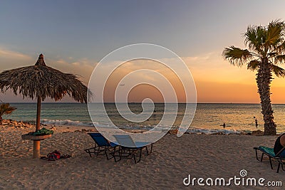 Amazing sunset on sandy beach and Atlantic Ocean. Sun beds and umbrellas on turquoise water and blue orange sky background. Stock Photo