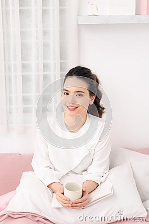 Amazing time to relax with favourite book and coffee. White bedroom shot Stock Photo