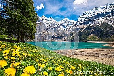 Amazing tourquise Oeschinnensee with waterfalls, wooden chalet and Swiss Alps, Berner Oberland, Switzerland Stock Photo