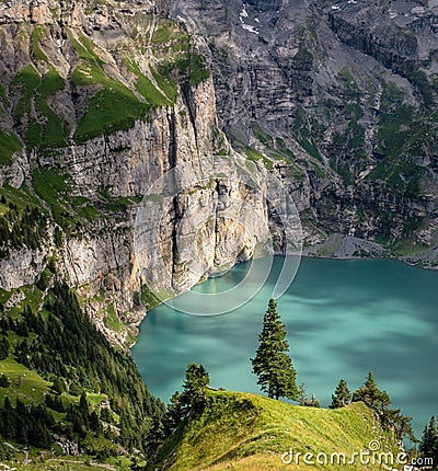 Amazing tourquise Oeschinnensee with waterfalls, wooden chalet and Swiss Alps, Berner Oberland, Switzerland. Stock Photo