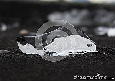 Amazing transparent blue iceberg pieces on Diamond beach with black sand near Jokulsarlon lagoon, Iceland. Ice calving. Black and Stock Photo