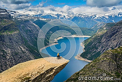 Amazing view with Trolltunga and a girl sitting on it. Norway Stock Photo