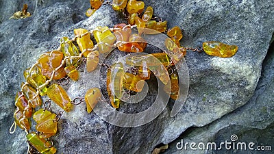 An amber Baltic jewelry necklace and a handmade bracelet on the stone. Stock Photo