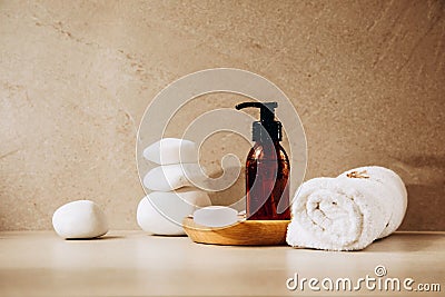 Amber bottle with cosmetics with drops of water on a wooden plate on a beige background with white stones Stock Photo