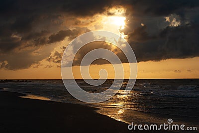 Amber colored sunset along shoreline Stock Photo