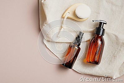 Amber glass bottles with body lotion and shampoo and facial cleansing brush on beige background. Skin care concept Stock Photo