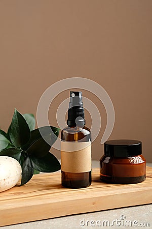 Amber glass cosmetic bottles, homemade soap, green leaves on wooden board, Natural organic cosmetics, SPA beauty product packaging Stock Photo